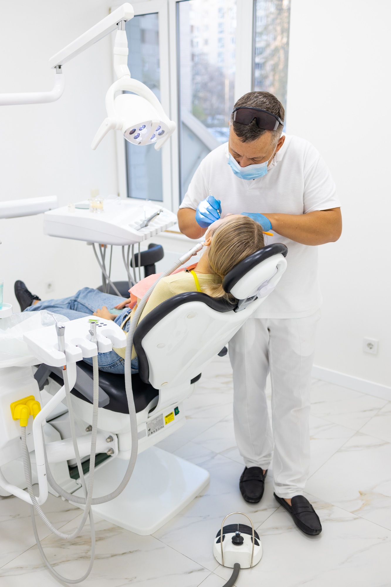 Male dentist treating teeth to young woman patient in clinic. Dental check up.